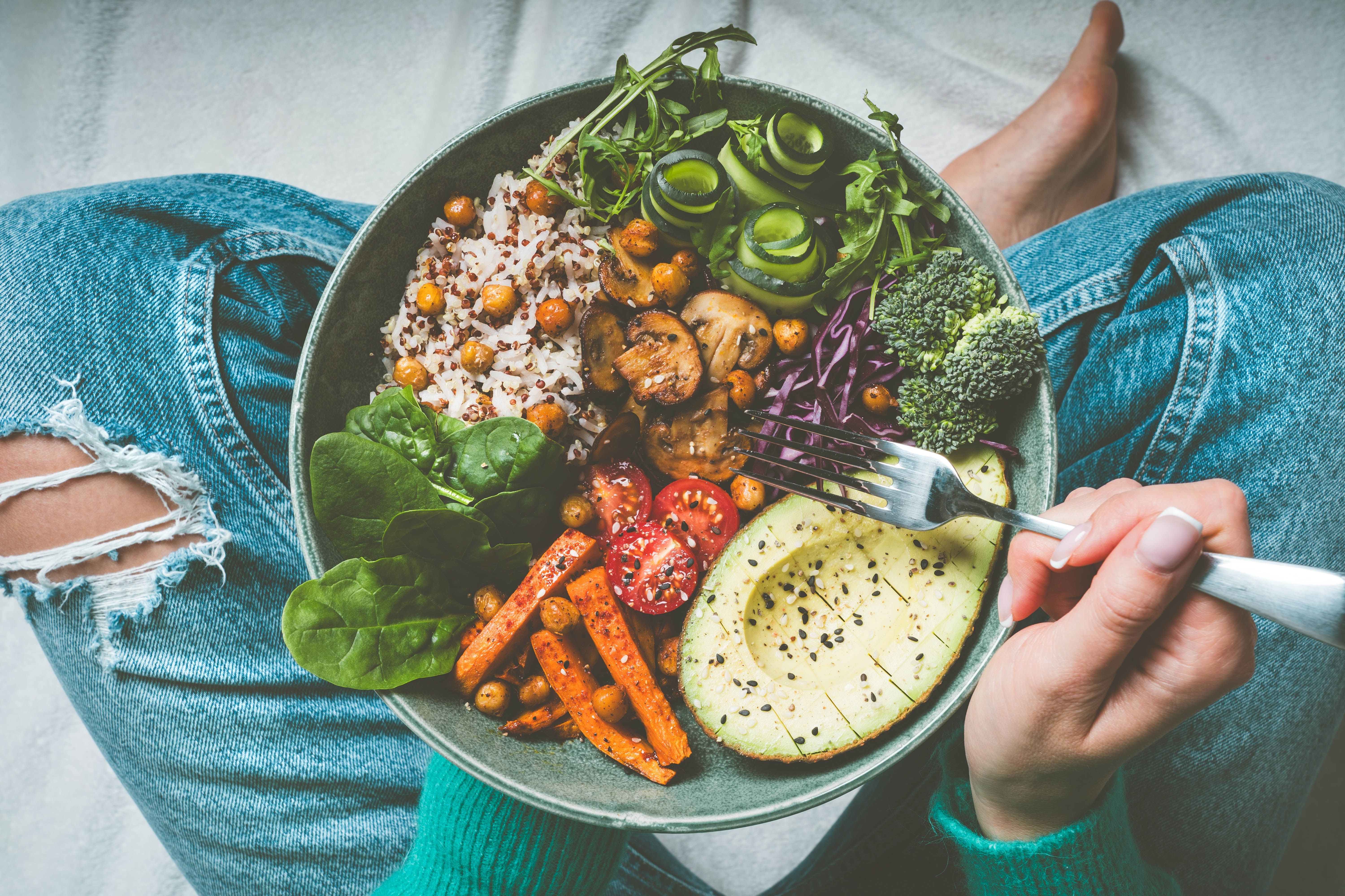 Woman sitting cross-legged with a big healthy salad on her lap Woman sitting cross-legged with a big healthy salad on her lap